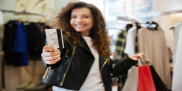 Retail shopper proudly using store loyalty card in boutique