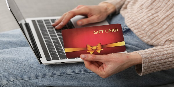 Customer holding a digital gift card while shopping online, highlighting the need for more personalized gifting than generic gift cards.
