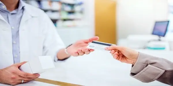 Patient handing a card to healthcare staff, illustrating how loyalty programs improve patient engagement and healthcare experiences.