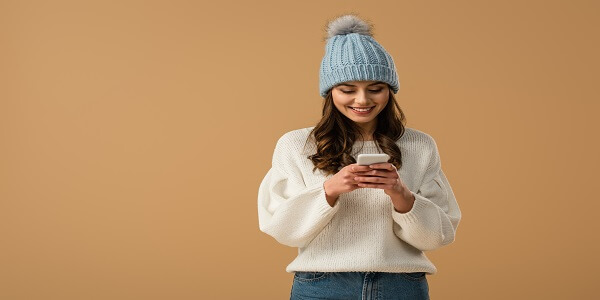 Smiling woman reading a message on her phone, showing how strong brand communication helps attract and engage customers.