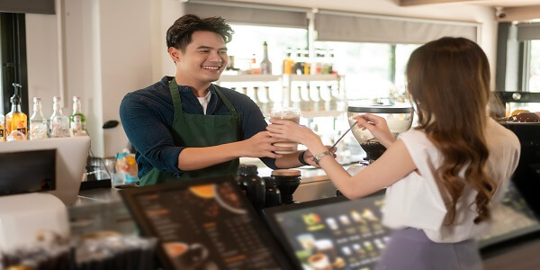 Barista handing a drink to a happy customer, reflecting engaging reward experiences like Starbucks’ loyalty program.