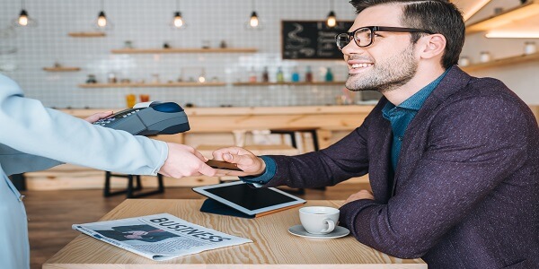 Business professional making a digital payment at a café, highlighting the effectiveness of payment-centric loyalty in B2B.