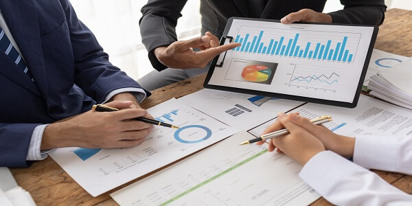 Team reviewing financial charts and forecasts, illustrating future market standards for agile retail bank loyalty programs.