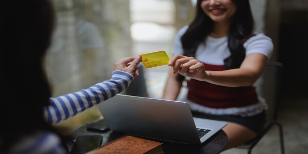 Customer handing loyalty card to cashier in café