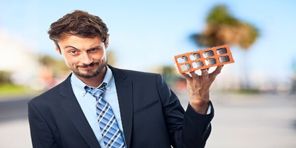 Smiling businessman holding a brick, symbolizing the challenges and tips to avoid limitations in building a loyalty points system.