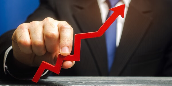 Business professional holding an upward arrow, symbolizing strategies to boost sales during a slow growth year.