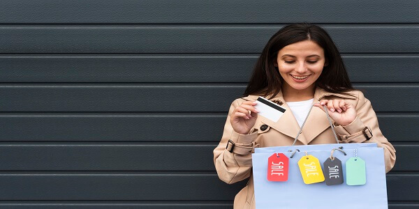 Smiling shopper holding a card and sale bags, showing how choosing the right loyalty program can attract potential loyal customers.