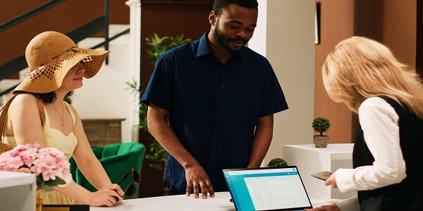 Hotel staff assisting guests at the front desk, illustrating steps to deliver an enhanced and seamless customer experience.