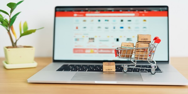 Mini cart with packages on a laptop, symbolizing key considerations for eCommerce brands before creating paid loyalty programs.