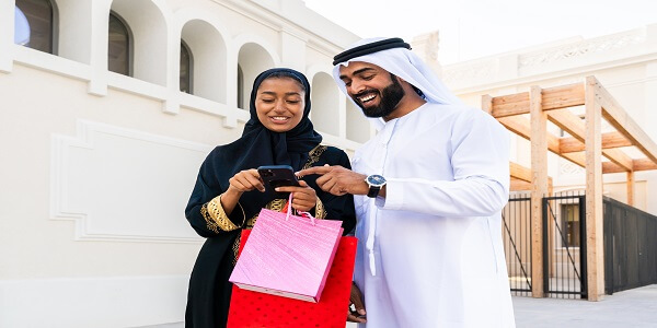 Emirati couple in traditional abaya and kandura enjoying time together in a modern Middle Eastern city, representing the theme of ‘Middle East Loyalty Programs: More Than Just Monetary Rewards.