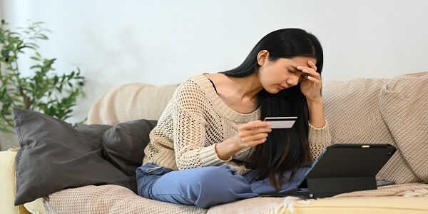 A woman looking stressed and frustrated while facing difficulties with an online payment using her credit card, representing common customer challenges and mistakes in loyalty program transactions.