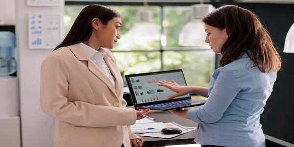 Two business professionals discussing customer data and growth analytics on a laptop, representing Customer Lifetime Value (CLV) optimization in loyalty programs.