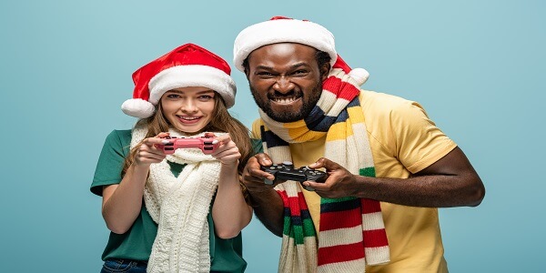 Two friends in Christmas hats playing video games, symbolizing fun gamification ideas that turn holiday cheer into customer loyalty.